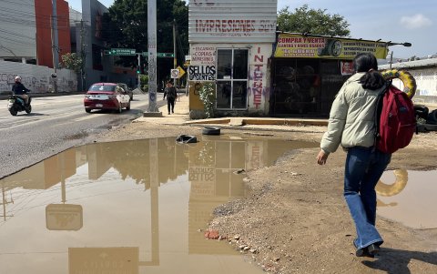 Personas caminan entre agua estancada por una calle, este viernes en Oaxaca (México).