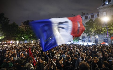 Una persona ondea una bandera francesa mientras la gente reacciona después de los resultados de la segunda vuelta de las elecciones legislativas, el 7 de julio de 2024.