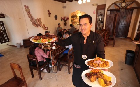 El mesero de Mamá Lola lleva el pollo acuyado, la cecina de cerdo y un cuy asado.