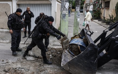 Agentes de las fuerzas de seguridad brasileñas reabren una calle que ha sido cercada para evitar el ingreso de las autoridades en una de las favelas de Río de Janeiro (Brasil).