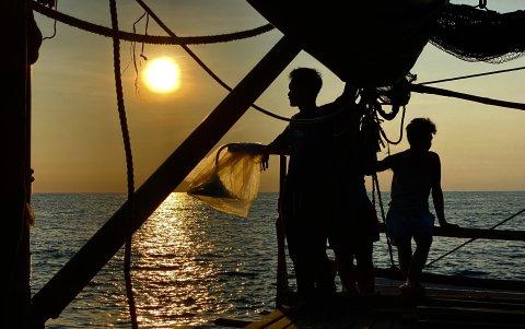 Pescadores filipinos a bordo de un barco de madera motorizado mientras navegan por las aguas del disputado mar de China Meridional, el 16 de mayo de 2024.