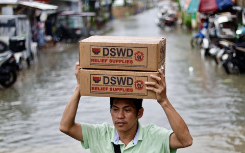 Un aldeano lleva cajas de ayuda durante una operación de distribución de ayuda en la ciudad de Cavite, Filipinas, el 23 de julio de 2024.