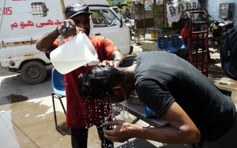 Un hombre intenta refrescarse vertiéndole agua en la cabeza en un campamento al borde de la carretera en Karachi, Pakistán, el 21 de julio de 2024.