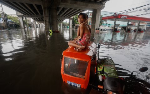 Una niña se sienta encima de un triciclo en medio de las inundaciones provocadas por las lluvias monzónicas en Quezon City, Metro Manila, Filipinas, el 24 de julio de 2024.