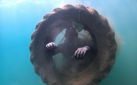 Uno de los buzos acompaña la extracción desde el fondo marino, un neumático.