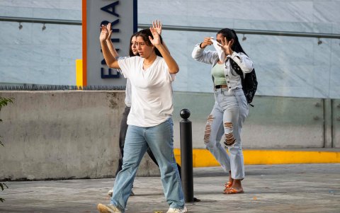 Tres jóvenes avanzan con las manos arriba para evitar ataque de integrantes de la Policía Nacional Bolivariana.