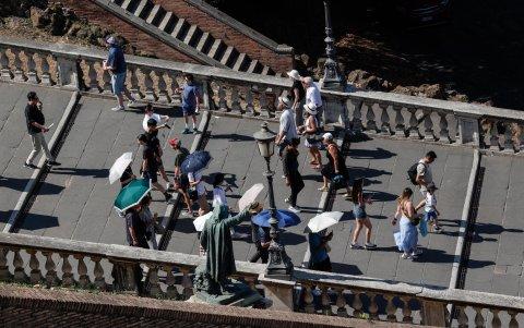 La gente sostiene paraguas para protegerse de la luz solar durante un caluroso día de verano en Roma.