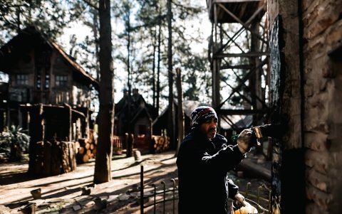 Un hombre pinta la pared de una casa en el asentamiento 'medieval' en el municipio bonaerense.
