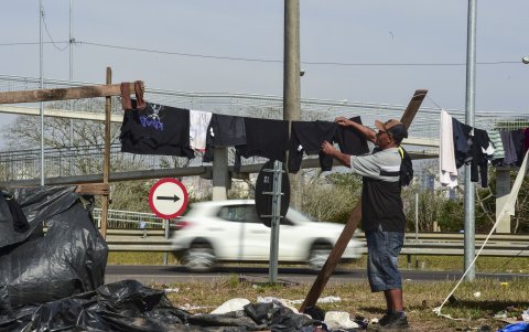 Un hombre mientras cuelga su ropa al lado de la BR-290, una de las principales carreteras de Río Grande do Sul (Brasil).