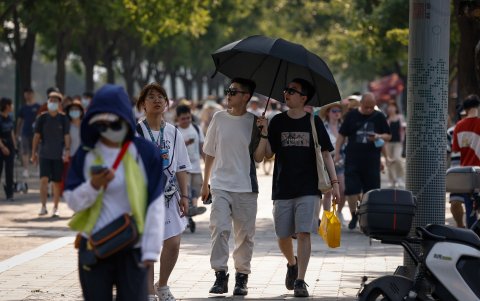 Varias personas transitan por un sector turístico de Pekín, en una día de mucho sol.