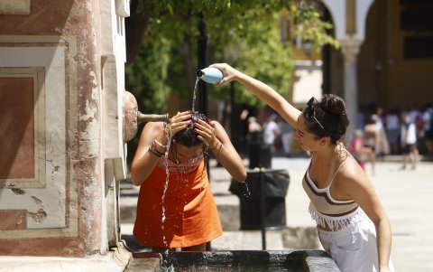 Dos mujeres se refrescan en una fuente del Patio de los Naranjos de la Mezquita Catedral de Córdoba.