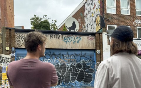 Dos personas observan uno de las últimas obras del célebre artista urbano británico conocido como Banksy, antes de que sea robada.