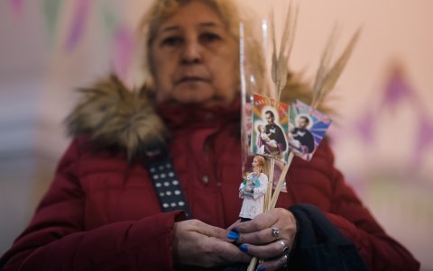 Una mujer sostiene imágenes de un santo.
