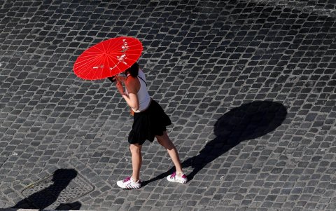 Una mujer porta una sombrilla para protegerse del sol en un caluroso día en Roma.