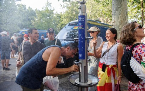 Ciudadanos se refrescan junto a un dispensador de agua en París ante las altas temperaturas.