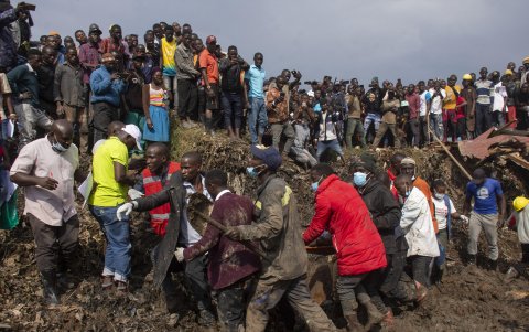 Varias personas llevan a un superviviente a un lugar seguro durante las labores de rescate tras el deslizamiento de tierra que sepultó casas en un vertedero en el distrito de Kiteezi.