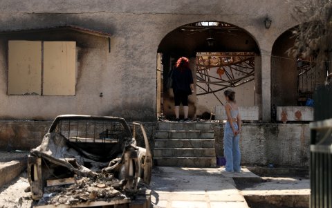 Dos mujeres aparecen paradas en la entrada de una casa quemada en la zona de Chalandri, cerca de la ciudad de Atenas, Grecia, el 13 de agosto de 2024.