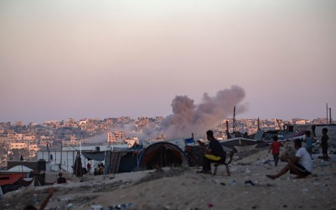 El humo se eleva tras un ataque aéreo israelí mientras los palestinos desplazados internos en el campamento de Khan Younis, en el sur de la Franja de Gaza, el 13 de agosto de 2024.
