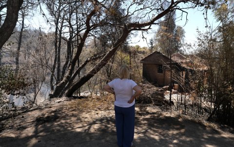 Una mujer se encuentra frente a una casa quemada después de un incendio forestal en la zona de Nea Penteli, cerca de Atenas, Grecia, el 13 de agosto de 2024.