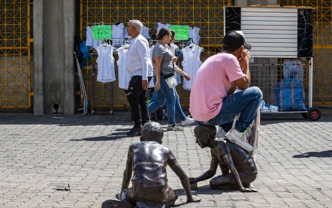 Una persona sentada sobre la estatua de una niña en el Boulevard Sabana Grande