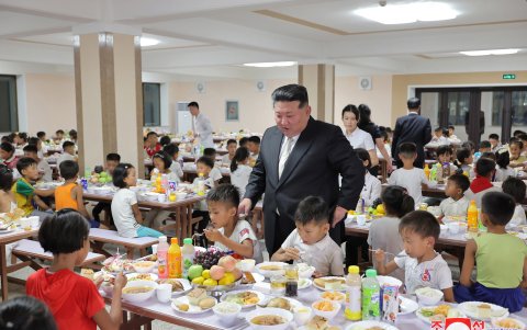 El líder Kim Jong-un, mira a unos niños comiendo durante una visita a los alojamientos de las víctimas de diferentes zonas afectadas por las inundaciones en Pyongyang