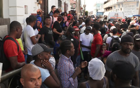 Migrantes hacen fila a la espera de resolver su situación migratoria en México.