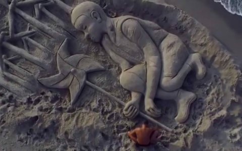 En la captura de vídeo, se observa al artista italiano Nicola Urru y a la escultura de arena.