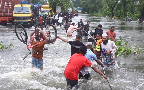 La gente camina sobre el agua de una inundación en la carretera después de una inundación repentina generalizada en el distrito de Feni, Bangladesh, el 22 de agosto de 2024.