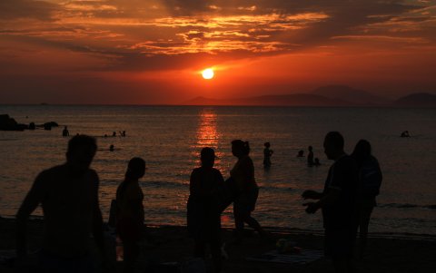 La gente disfruta de la puesta de sol desde la playa de Kavouri, al sur de Atenas (Grecia)