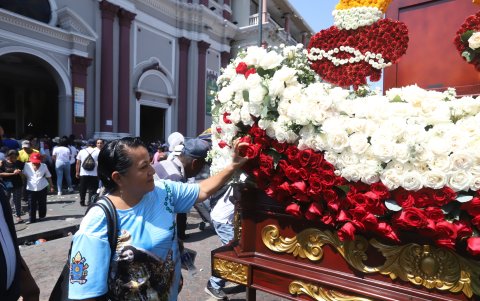 La imagen de la virgen es adornada con flores.