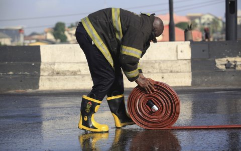 Un bombero nigeriano enrolla una manguera. Un camión cisterna de gasolina el domingo debido a un accidente en una importante carretera del estado de Níger