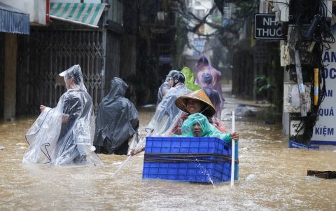 Residentes locales con sus mercancías caminan por las aguas de la inundación en una calle de Hanoi, Vietnam, el 11 de septiembre de 2024.