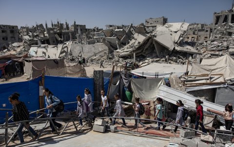 Niños palestinos pasan junto a edificios destruidos mientras se dirigen a clases en el campamento de Khan Younis, en el sur de la Franja de Gaza, el 12 de septiembre de 2024.