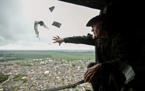 Un oficial de la Policía lanzando volantes informativos desde un helicóptero en la región de Urabá en una campaña para invitar a la comunidad a denunciar la ubicación de los jefes del Clan del Golfo.