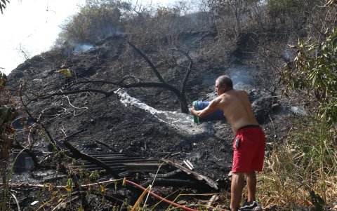 Un habitante del sector San Pablo lanza agua para evitar que las llamas vuelvan a encenderse.
