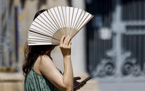 Una mujer se protege del intenso calor con un abanico en alguna ciudad del mundo.