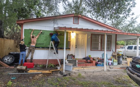 Varias personas tapian las ventanas de una casa para prepararse para el huracán Helene, en Old Town, Florida, EE.UU., 25 de agosto de 2024.