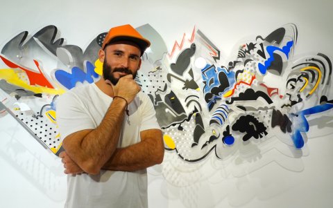El artista puertorriqueño, Edwin Maurás Maldonado, posando frente a una de sus obras.