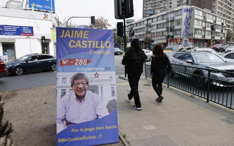 Personas caminan frente a un afiche con propaganda electoral en Santiago (Chile)