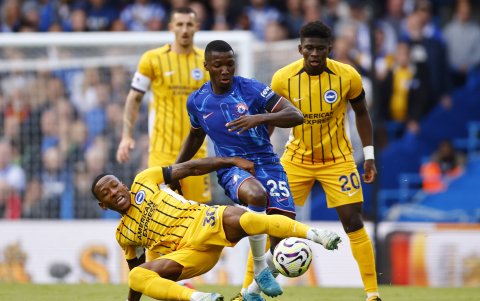 Pervis Estupiñán (piso) de Brighton defiende la pelota ante Moisés Caicedo (c) de Chelsea
