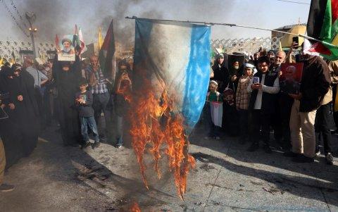 La gente quema una bandera israelí mientras se reúne para una manifestación contra Israel.