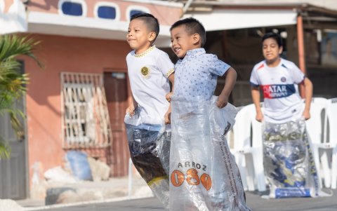 Varios niños compiten para llegar a la meta dentro de un saco, como parte de las tradiciones de antaño.