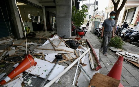 Una persona atraviesa cerca de una acera ocupada por los desechos de los daños que provocó el tifón Krathon.