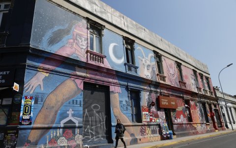Fotografía del 25 de septiembre de 2024 de una persona caminando junto a un mural en el Barrio Yungay, en Santiago (Chile).