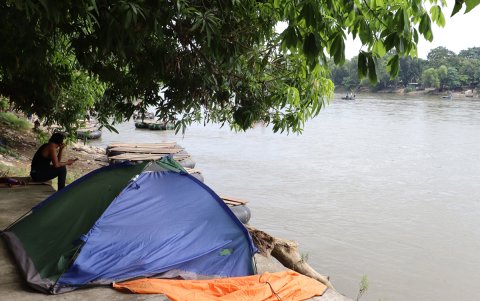 Un migrante descansa junto a una tienda campaña a la orilla del río Suchiateen