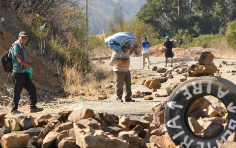 Varias personas atraviesan una carretera en Epizana, departamento de Cochabamba (Bolivia), bloqueada.
