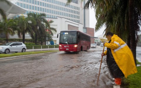 Un hombre que destapa un desagüe en una vía inundada debido a las intensas lluvias provocadas en Cancún (México).