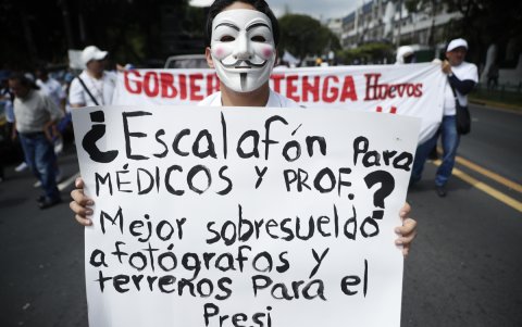 Un manifestante sostiene un cartel en una marcha este sábado 19 de octubre en San Salvador (El Salvador).