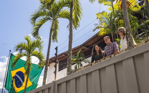 Claudia Macero (i), Pedro Uchurrurtu y Magalli Meda, asilados en Embajada de Argentina, saludan a los medios de comunicación desde un balcón con la bandera de Brasil a un costado, en Caracas.