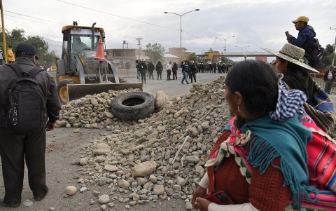 Una mujer camina en medio del bloqueo a una calle por parte de seguidores del expresidente Evo Morales (2006-2019) este martes, en Vinto (Bolivia).